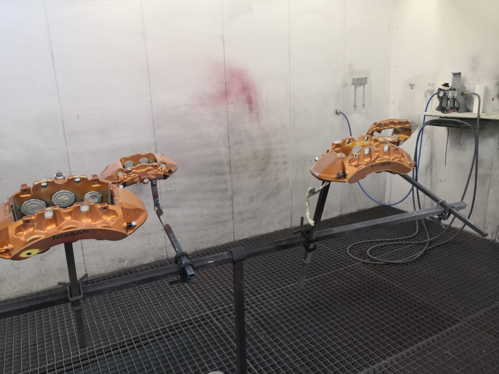 Frisch lackierte orange Bremssättel in der Spritzkabine bei TUNA Fahrzeugtechnik