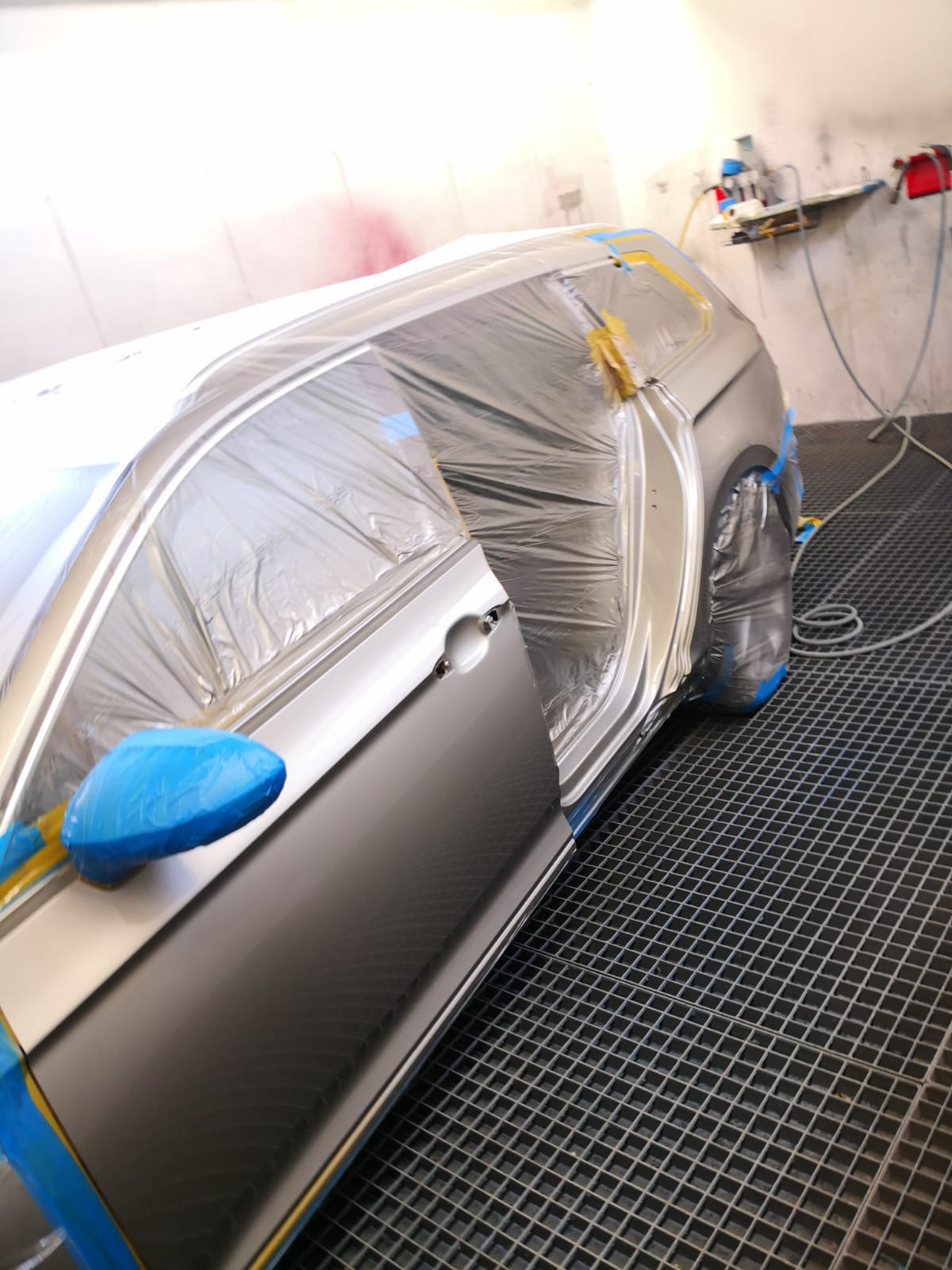 Geöffnete silberne Tür mit Grundierung in der Lackierkabine bei TUNA Fahrzeugtechnik