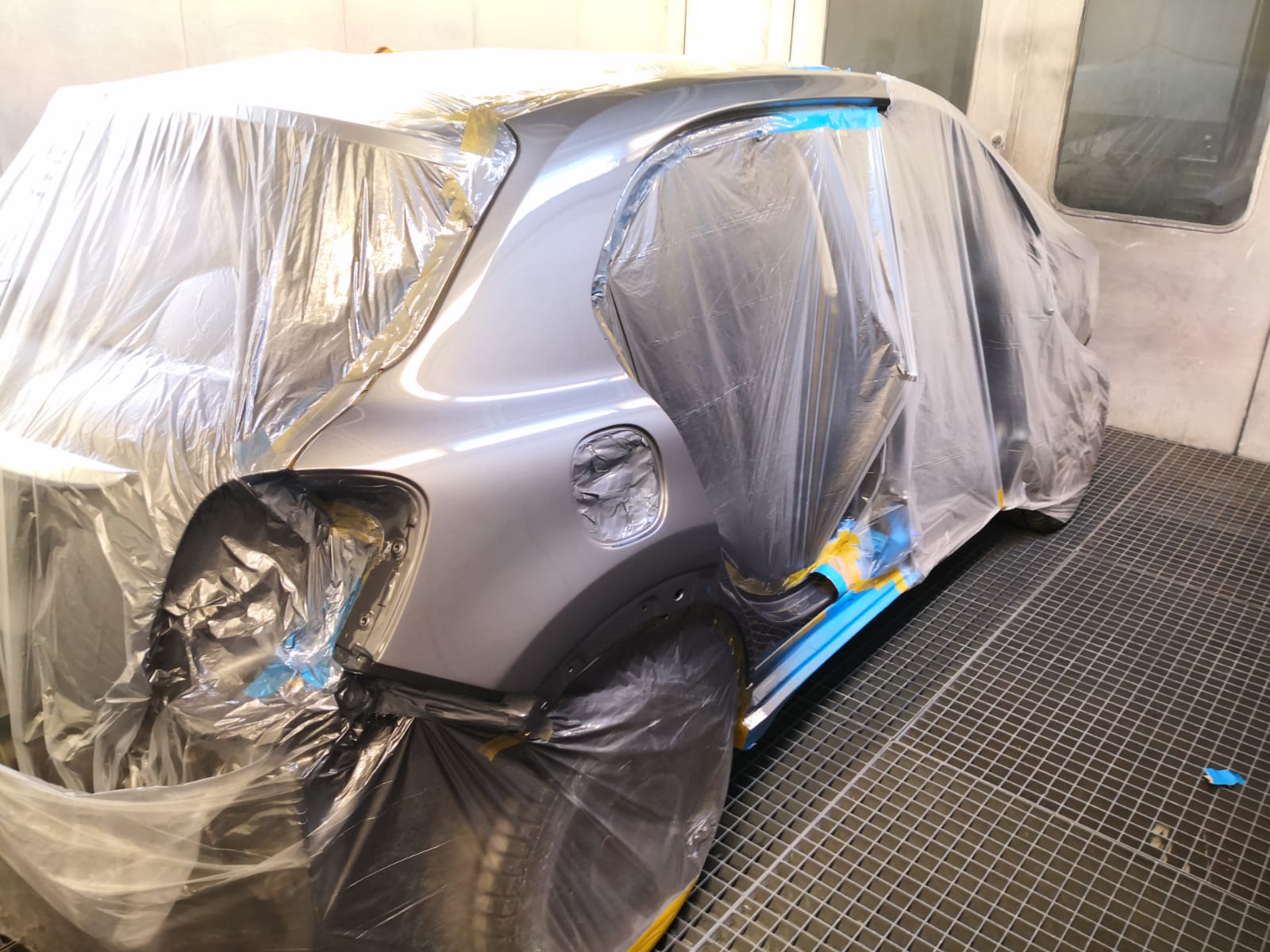 Graues Schrägheck mit abgeklebtem Heckseitenteil für die Lackierung in der TUNA Werkstatt