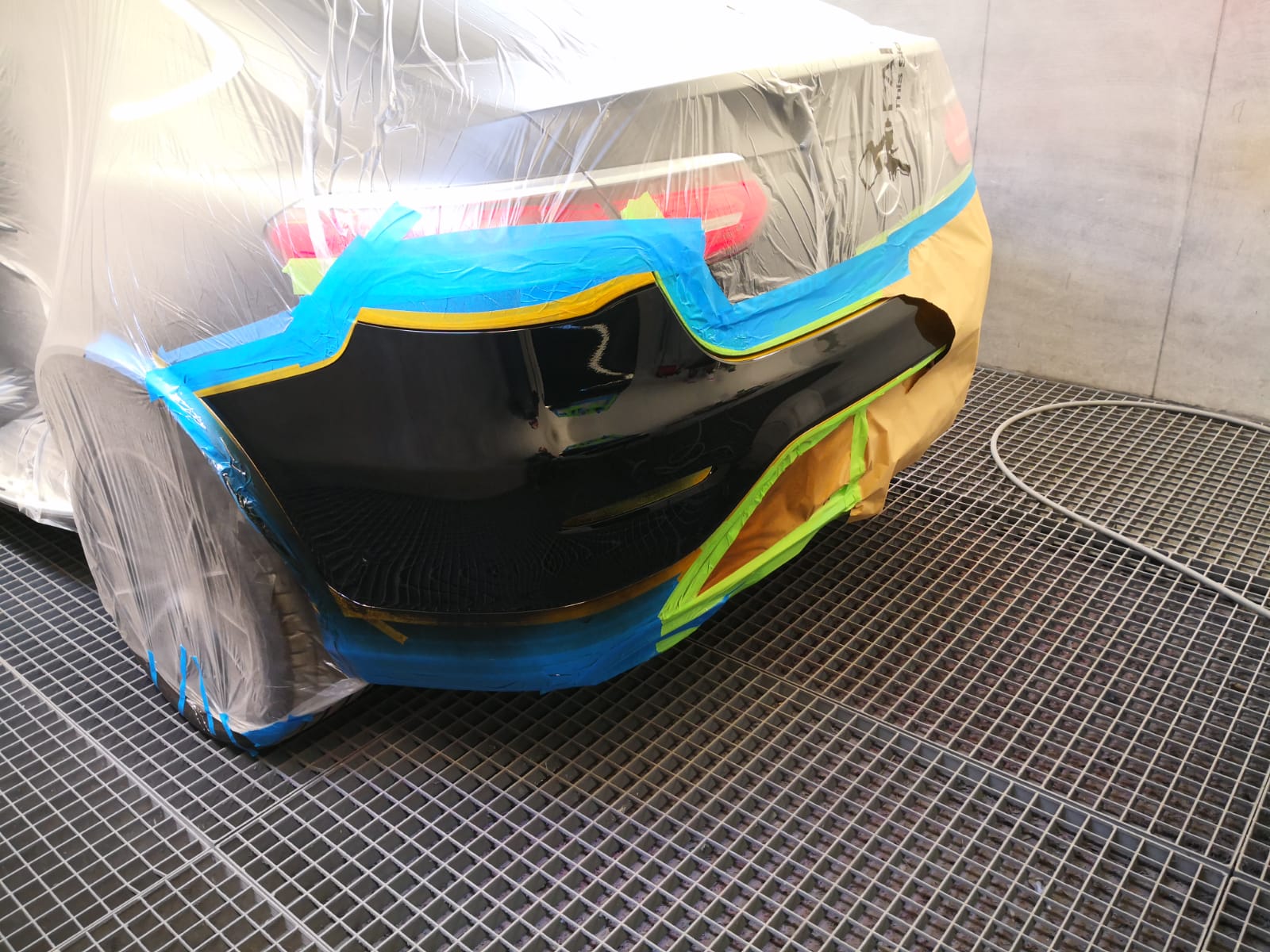 Schwarze Heckstoßstange abgeklebt und in der Lackierkabine bei TUNA Fahrzeugtechnik